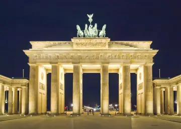 Nocą Brama Brandenburska w Berlinie, oświetlona, z Kwadrygą na szczycie.