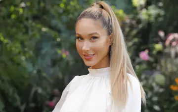 Ida Nowakowska zwolniona z TVP, uśmiechnięta blondynka w białej bluzce na tle zieleni.