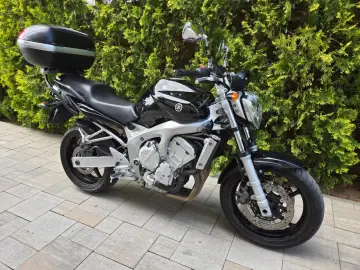 Czarny motocykl Yamaha Fazer 600 z kufrem, idealny na długie trasy. Sprawdź jego dane techniczne!