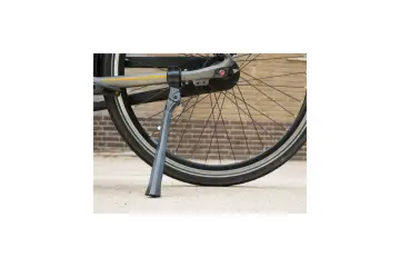 Szara stopka rowerowa podtrzymuje rower, opierając się o betonową nawierzchnię.