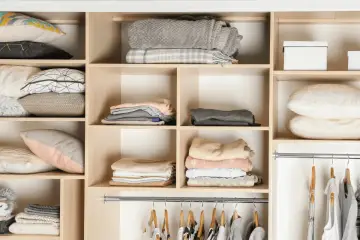 Ubrania i poduszki schludnie ułożone w regale. To przykład, jak moda cyrkularna może pomóc w organizacji i ponownym wykorzystaniu rzeczy.