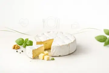 Pyszny camembert z białą pleśnią, z kawałkami i kostkami, obok bazylii i orzecha. Zastanawiasz się nad camembert kcal?