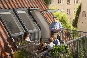 Rodzina gra w szachy na balkonie, który otwiera się jak okno dachowe z balkonem.
