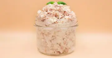 Pyszna pasta z tuńczyka i twarogu, doprawiona pieprzem, w słoiku, ozdobiona listkami bazylii. Idealna na kanapki.