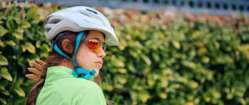 Młoda rowerzystka w kasku i okularach przeciwsłonecznych. Czy kask na rower jest obowiązkowy? Bezpieczeństwo przede wszystkim!