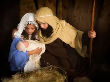Dzieci w strojach na jasełka: Maryja z Dzieciątkiem Jezus w ramionach, obok Józef z laską.