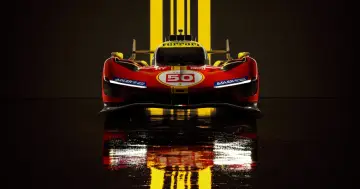 Wyścigowy Ferrari 499P w czerwono-żółtych barwach, z numerem 50, odbija się w mokrej nawierzchni.