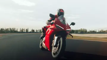 Czerwony motocykl Ducati Panigale V4 S pędzi po torze wyścigowym, kierowca w kombinezonie w tym samym kolorze.