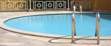 Błękitna woda w basenie, schody i ozdobne ogrodzenie. Dowiedz się, jak obliczyć pojemność basenu, by cieszyć się kąpielą.