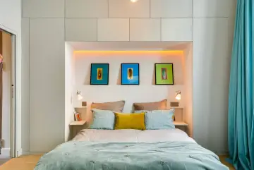 Idee salvaspazio camera da letto piccola: letto con testiera contenitore, quadri colorati e tende turchesi creano un ambiente accogliente.