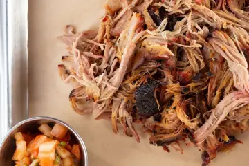 Zartes Pulled Pork, perfekt gegart, zeigt die ideale pulled pork kerntemperatur. Daneben eine Schale mit frischer Salsa.