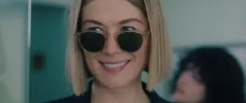 Uśmiechnięta Rosamund Pike w okularach przeciwsłonecznych, gwiazda filmów, seriali i programów.