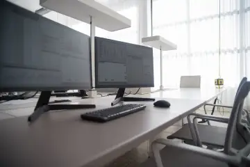 Jak ustawić dwa monitory na biurku? Dwa monitory z wykresami, klawiatura i myszka na biurku.