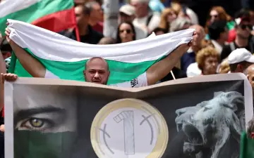 Mężczyzna z bułgarską flagą, pytający "czy Bułgaria jest w Unii?". Na transparencie widnieje oko i lew.