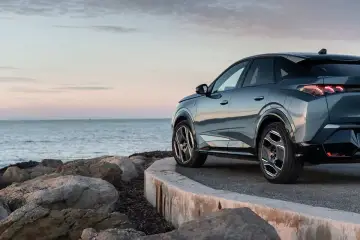 Nowy Peugeot 3008 hybryda na tle spokojnego morza i skalistego wybrzeża.