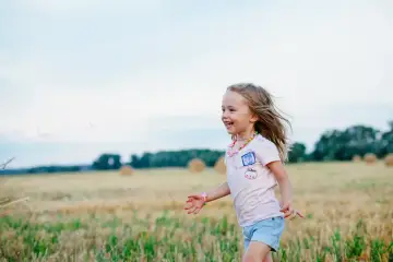 Szczęśliwa dziewczynka biega po polu. Czy dziecko musi iść do przedszkola, gdy świat jest tak piękny?