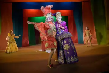 Aktorzy w barwnych strojach, niczym z komedii Moliera, pozują na scenie.