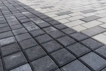 Szara i biała kostka brukowa ułożona w geometryczny wzór. Zastanawiasz się, ile kostki na m2?