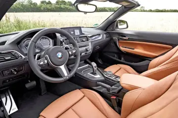 Wnętrze BMW f23 z brązową skórzaną tapicerką i sportową kierownicą.
