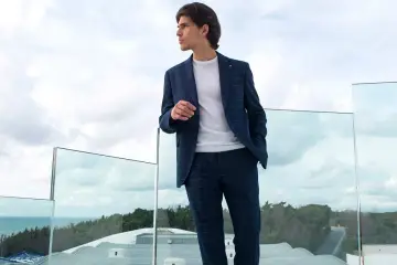 Uomo con tailleur blu a quadri, maglione bianco. Perfetto per capire con che scarpe abbinare.