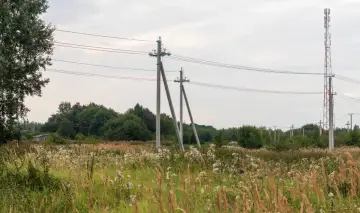 Słupy energetyczne i wieża telekomunikacyjna na tle nieba. Zastanawiasz się, ile pieniędzy za słup na działce?