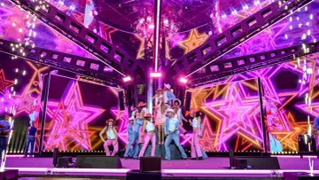 Artyści w kowbojskich kapeluszach i różowych strojach na scenie podczas Sylwestra z Polsatem.