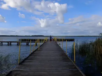 Drewniane molo nad jeziorem, z żółtymi poręczami, zaprasza do podziwiania widoków. To jedna z jezierzany atrakcji.