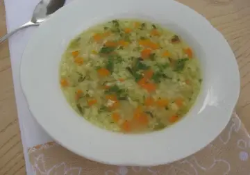 Pyszna ryżanka z marchewką i natką pietruszki, podana w białej miseczce, gotowa do jedzenia.