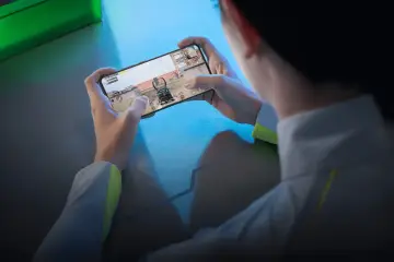 Gracz trzyma w dłoniach telefon do gier, zanurzony w wirtualnym świecie.