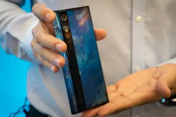 Ręce trzymające futurystyczny telefon Xiaomi Mi Mix Alpha z niebieskim, marmurkowym wzorem na obudowie.