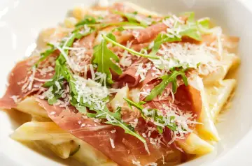 Penne z kremowym sosem, szynką parmeńską, rukolą i parmezanem. Pyszne makaronowe danie.
