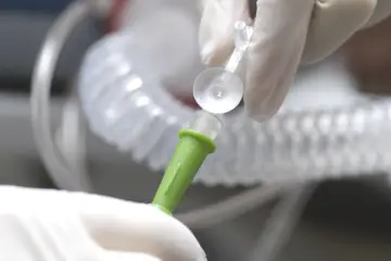 Hände in Handschuhen verbinden ein medizinisches Schlauchsystem. Mögliche Nachteile einer PEG-Sonde sind Infektionen und Verstopfungen.