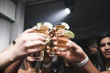 Ludzie wznoszą toast kieliszkami z tequilą lub mezcalem, zastanawiając się nad różnicą między nimi w klasycznej margaricie.