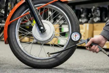 Sprawdzanie, jakie ciśnienie w oponach motocykla 125 jest optymalne, za pomocą manometru.