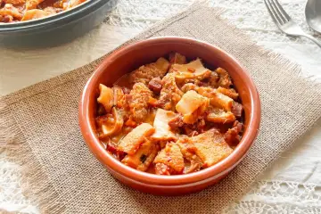 Un cuenco de barro con callos a la vizcaina, un plato tradicional español lleno de sabor y textura.
