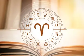 Zodiakalny baran i lew – ich związek bywa burzliwy, ale pełen pasji. Koło zodiaku na tle otwartej księgi.