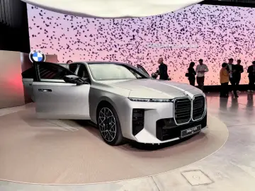 Eleganckie BMW M7 prezentuje się na wystawie, z otwartymi drzwiami, przyciągając uwagę gości.