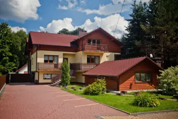 Jasny dom z czerwonym dachem, otoczony zielenią, to dom Adama Małysza w Wiśle.
