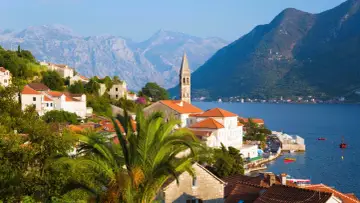 Perast, Czarnogóra – jedno z najpiękniejszych miejsc w Europie. Białe domy z czerwonymi dachami, palmy i góry nad błękitną zatoką.
