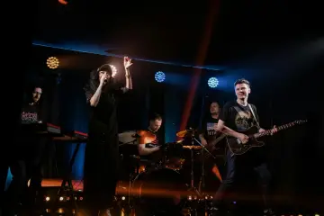 Zespół rockowy na scenie: wokalistka, gitarzysta, basista, perkusista i klawiszowiec. Koncert jak z listy zespoły rockowe zagraniczne alfabetycznie.