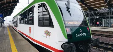 Pociągi do Władysławowa czekają na pasażerów na peronie. Zielono-biała lokomotywa z numerem SA133-012 gotowa do podróży.