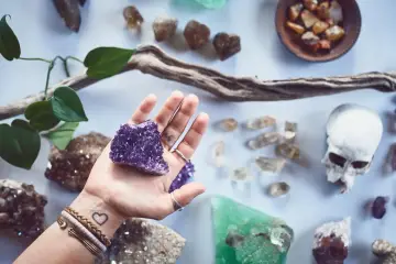 Mano sostiene amatista, rodeada de piedras y un cráneo. Un conjunto de piedras contra el mal de ojo y la envidia.