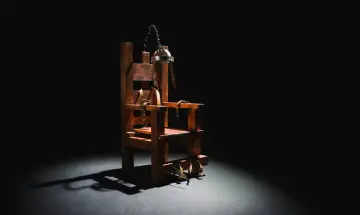 Drewniane krzesło z pasami i metalową obręczą, symbolizujące karę śmierci.