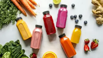 Kolorowe butelki z sokami, marchewki, szpinak i owoce – idealny zestaw na detox organizmu.