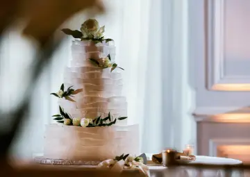 Elegancki tort piętrowy z kremowymi rozetami i kwiatami, idealny na uroczystość. Jak przewieźć tort piętrowy? Ostrożnie!