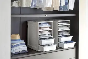 Organizzazione armadio: camicie piegate in contenitori modulari, pile di vestiti e un cappello su una mensola.
