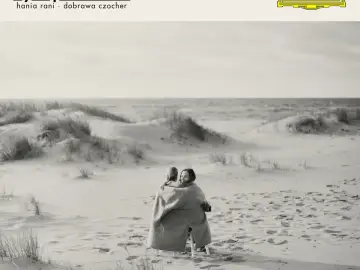 Dwie kobiety otulone kocem na plaży, słuchają **Hania Rani Inner Symphonies**.