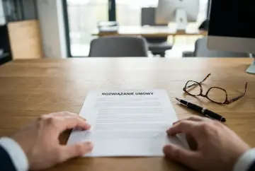 Dłoń na dokumencie "Rozwiązanie umowy", obok długopis i okulary. To moment, gdy zastanawiasz się, jak się pisze wypowiedzenie z pracy.