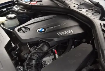 Silnik BMW TwinPower Turbo, prawdopodobnie 2.0 diesel, z widocznym logo BMW i elementami osprzętu.