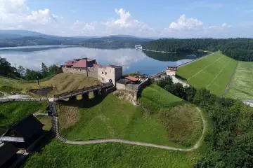 Zamek na wzgórzu nad jeziorem Dobczyckim. Atrakcje turystyczne obejmują zamek, zaporę i malownicze widoki.